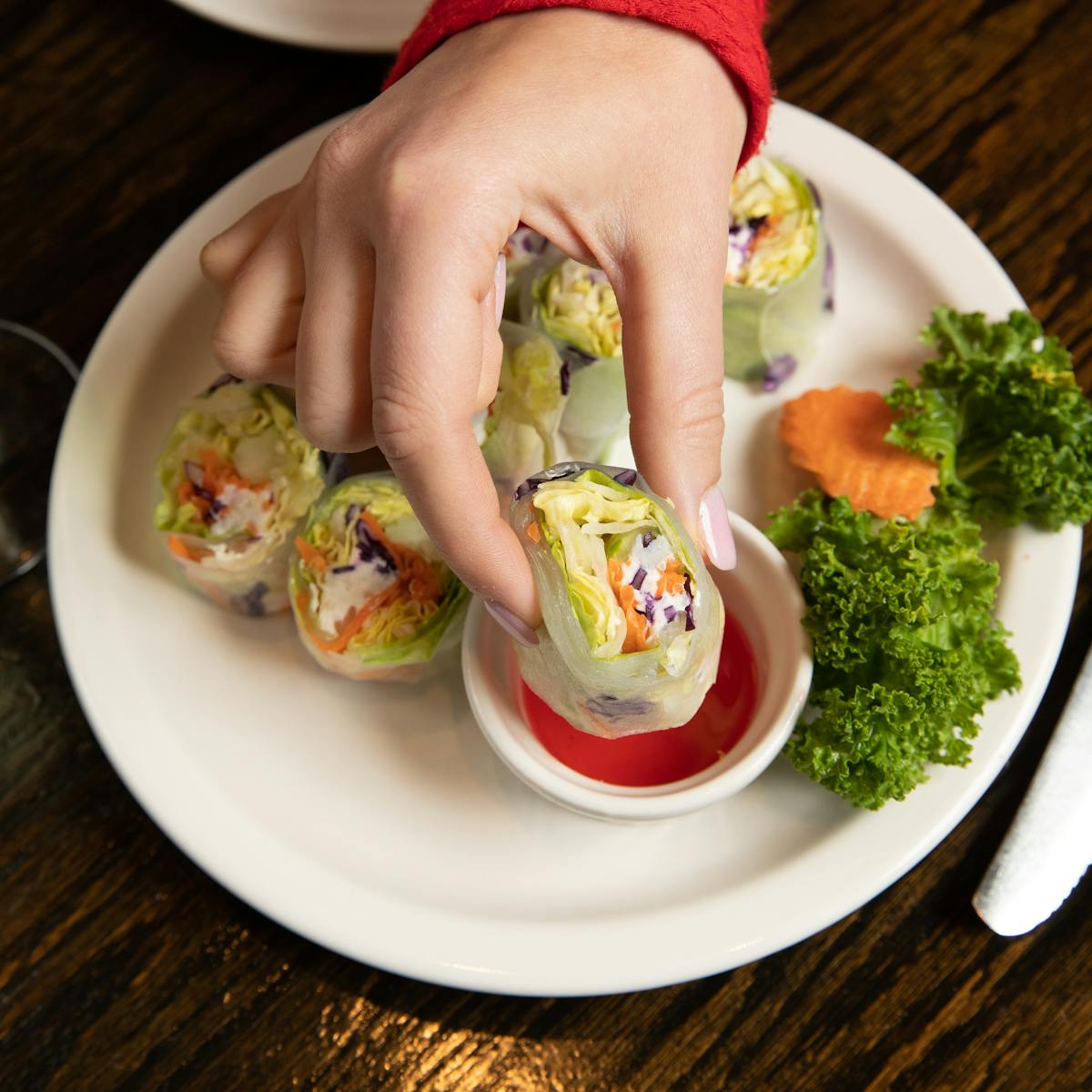 a person holding a plate of food on a table